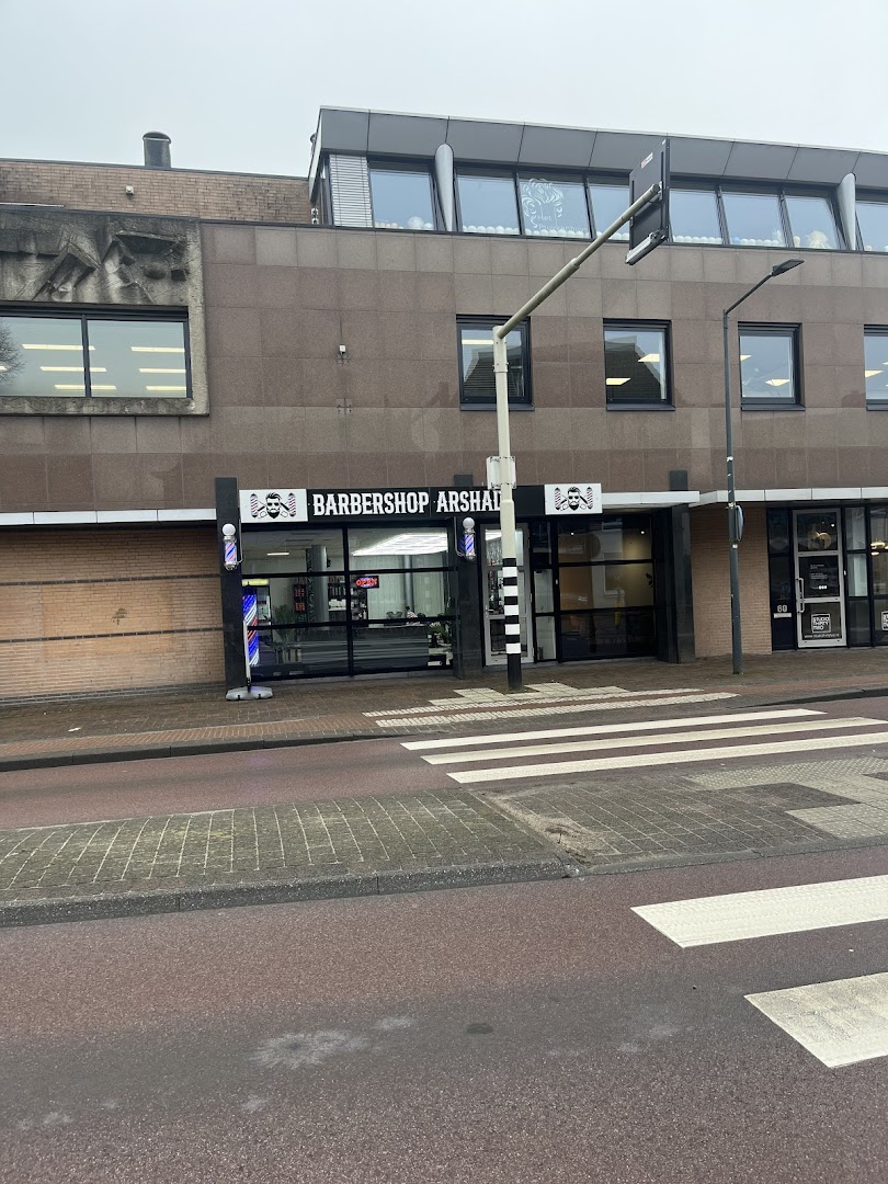 De gevel van Barbershop Arshad aan de Sint Bavostraat in Rijsbergen, met het zwarte uithangbord in goud en twee barbierpalen als logo