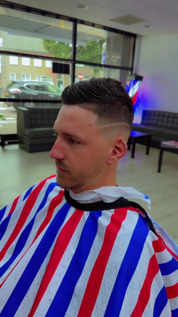 Klant met afgewerkt kapsel opzij, met het echte interieur van Barbershop Arshad zichtbaar op de achtergrond